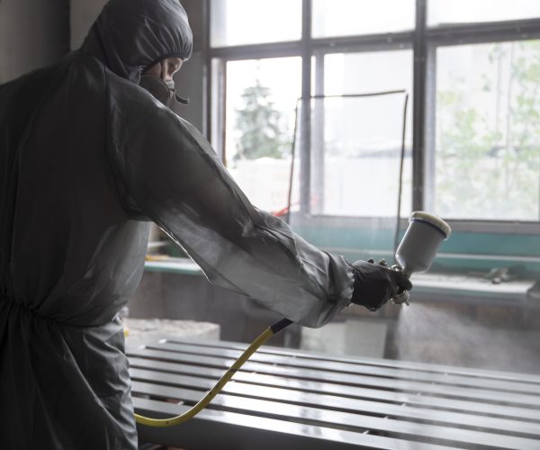 side-view-man-spraying-powder-paint-from-gun